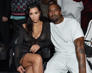 A couple sitting together at an event, the woman is in a black dress and the man in a white shirt, both gazing at the camera.