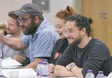 Cast members of Game of Thrones, including Sophie Turner, smiling and engaging during a table read session.