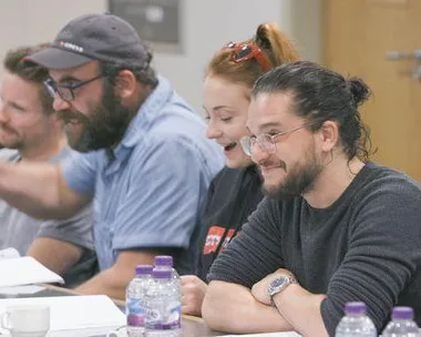 Cast members of Game of Thrones, including Sophie Turner, smiling and engaging during a table read session.