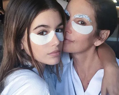 Two women wearing under-eye patches and robes, close together, showcasing a skincare routine.