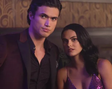 Young couple in evening wear at a fancy event, with a glamorous setting and vintage-style wallpaper.