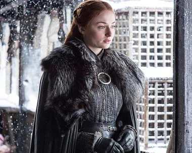 Sansa Stark stands in the snow wearing a fur cloak in "Game of Thrones".