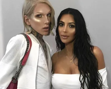 Jeffree Star and Kim Kardashian posing together, both in white outfits, with Star holding a red handbag.