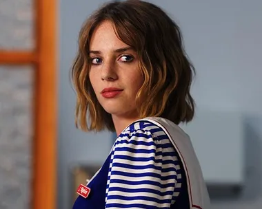 Young woman in a blue and white striped uniform, looking sideways, possibly a character from a popular Netflix show.