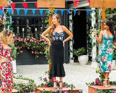 Three women in floral dresses stand on podiums at an outdoor event with colorful bunting and floral decorations.