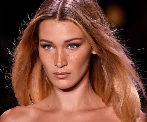 Close-up of a model with long, flowing hair on a runway.