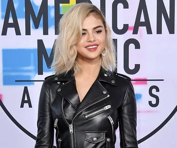 A person with short blonde hair in a black leather jacket at the American Music Awards.