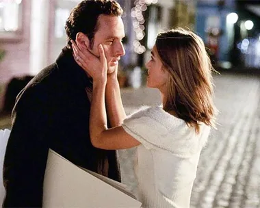 A romantic evening scene with a woman holding a man's face on a cobblestone street.