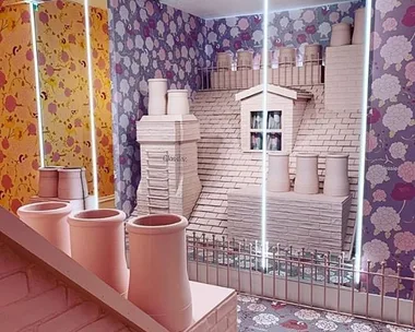 "Glossier London pop-up featuring a whimsical rooftop display with pastel chimneys and floral wallpaper."