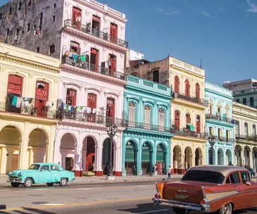 Colorful colonial buildings in Havana, Cuba with vintage cars on the street.