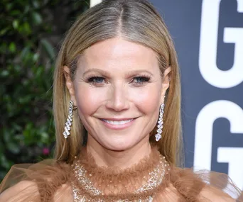 Smiling woman with long hair and diamond earrings at an event.