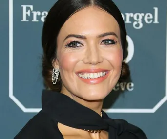 Smiling woman on the Critics' Choice Awards 2020 red carpet, wearing elegant jewelry and a black outfit.