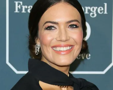 Smiling woman on the Critics' Choice Awards 2020 red carpet, wearing elegant jewelry and a black outfit.