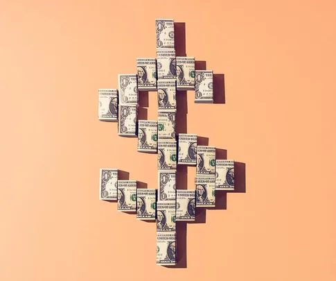 Dollar bills arranged in a dollar sign shape on a peach background.