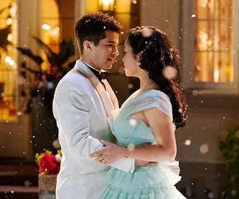 Lara Jean and John Ambrose dance outside in formal attire, surrounded by softly falling snow.