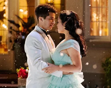 Lara Jean and John Ambrose dance outside in formal attire, surrounded by softly falling snow.