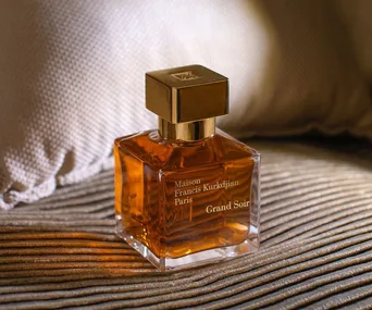 Maison Francis Kurkdjian Grand Soir perfume bottle on a textured surface, with a warm lighting ambiance.