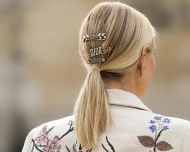 Blonde hair in low ponytail with embellished Dior clips, floral embroidered jacket.