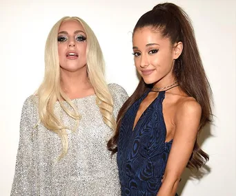 Two women posing together; one in a silver dress with long blonde hair, the other in a blue dress with brown hair.