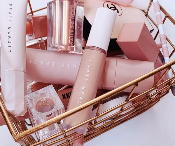 Basket containing Fenty Beauty makeup products, including lipsticks and foundation, in a neat arrangement.