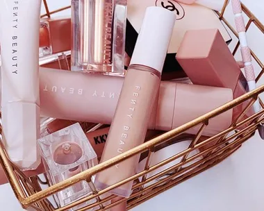 Basket containing Fenty Beauty makeup products, including lipsticks and foundation, in a neat arrangement.