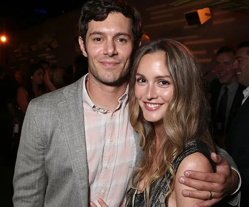 A couple smiling at an event with dim lighting in the background.