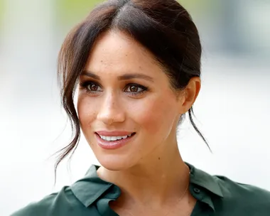 Woman with brown hair styled in a messy bun, smiling, wearing a green blouse.