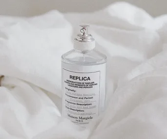 Maison Margiela Replica perfume bottle on white fabric background.