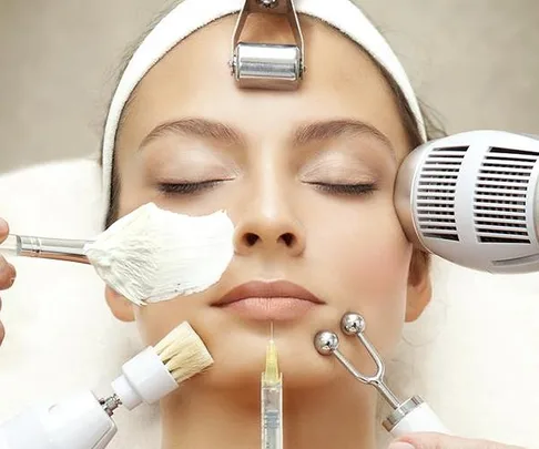 Woman receiving various beauty treatments, including facial cream, microdermabrasion, and anti-aging devices.