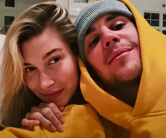 A couple wearing yellow hoodies, smiling close together, indoors.