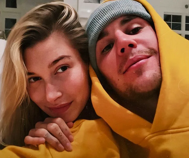 A couple wearing yellow hoodies, smiling close together, indoors.