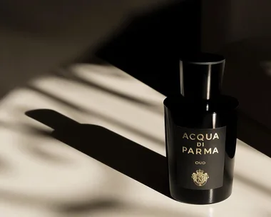 Acqua di Parma Oud perfume bottle casting a shadow on a light surface.