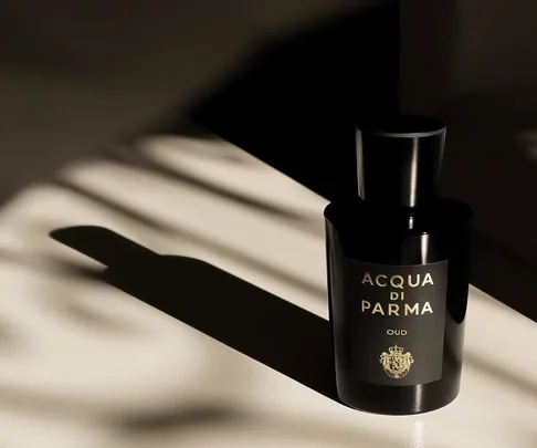 Acqua di Parma Oud perfume bottle casting a shadow on a light surface.