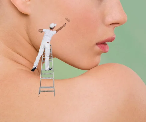 A tiny painter stands on a ladder applying makeup to a large woman's cheek, demonstrating creative pimple coverage.