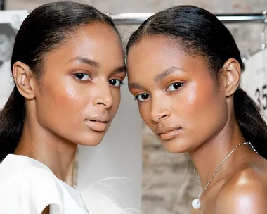 Two models with glowing skin and sleek hair pose together, highlighting a retinol-enhanced complexion.