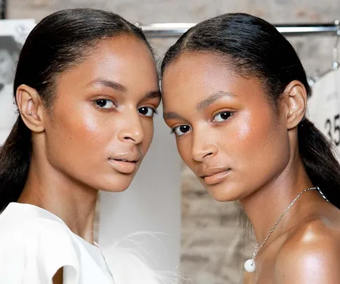 Two models with glowing skin and sleek hair pose together, highlighting a retinol-enhanced complexion.