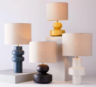 Stylish modern table lamps in various shapes and colors on pedestals.