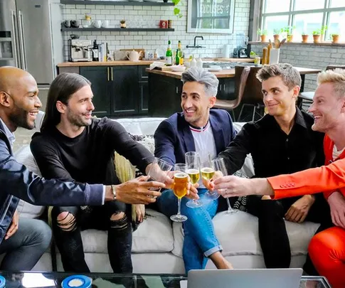 The "Queer Eye" cast toasting with drinks on a modern kitchen set.