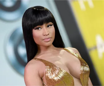 A woman with long black hair in a golden dress looks to the side at an event.