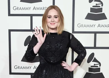 Singer waving at the Grammy Awards in a black dress.