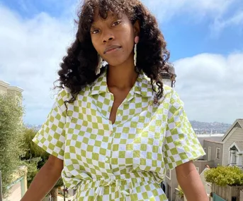 Woman wearing a green and white checkered shirt standing outside on a sunny day.