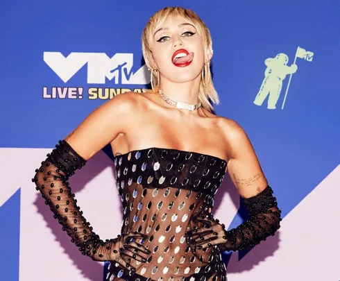 A person with short hair in a black and sheer dress poses on the 2020 VMA red carpet.