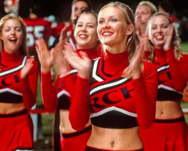 Cheerleaders in red uniforms perform energetically during a sports event.