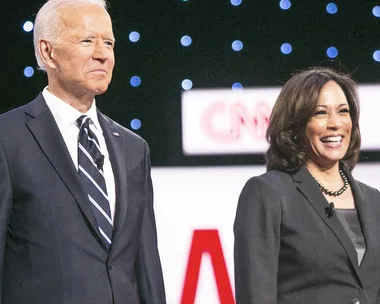 A man and a woman standing on a stage with a CNN logo in the background, smiling at an event.