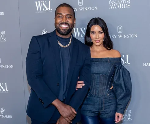 A man and woman pose together on a red carpet in elegant attire at an event.