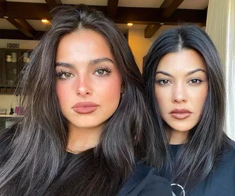 Two women with long dark hair and neutral expressions pose indoors, facing the camera.