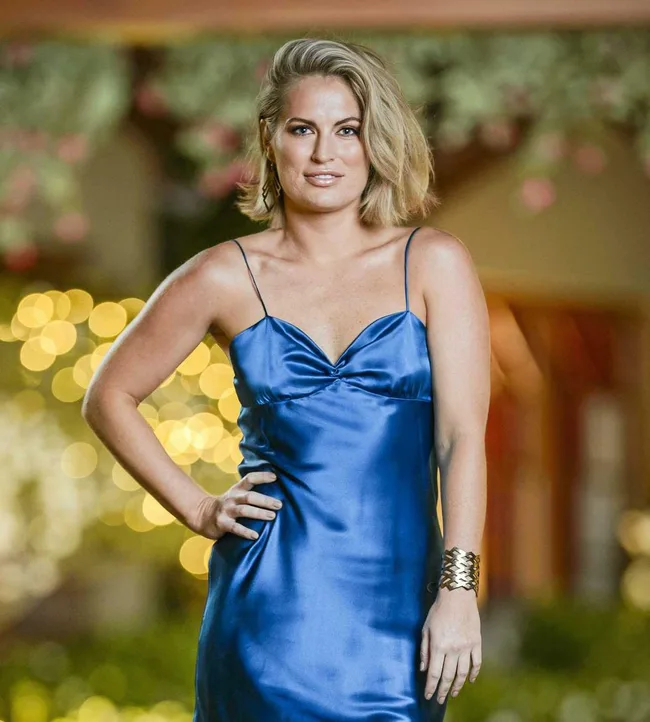 Woman in a blue satin dress poses, with bokeh lights in the background.