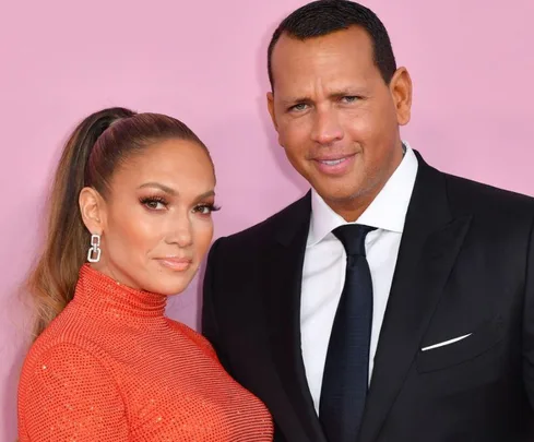 A couple posing in formal attire against a pink background.