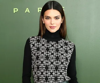 Person in patterned black and white outfit against a green backdrop.