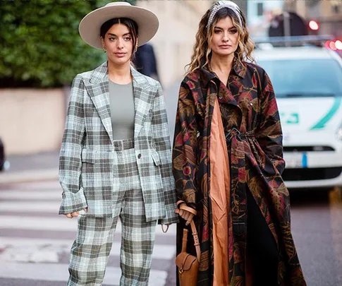 Two women in street style; one in a plaid suit with a hat, the other in a floral coat; Milan Fashion Week 2020.